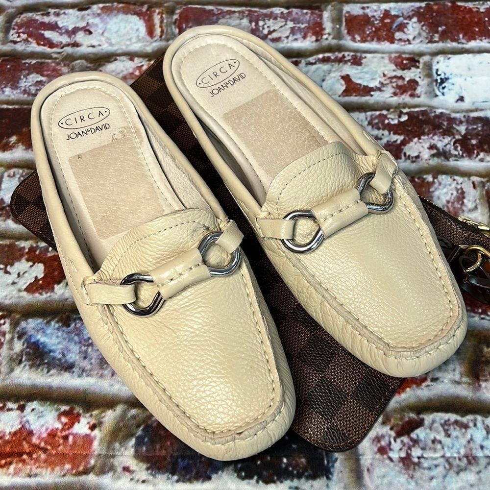* Joan & David cream leather slides with silver buckle detail.